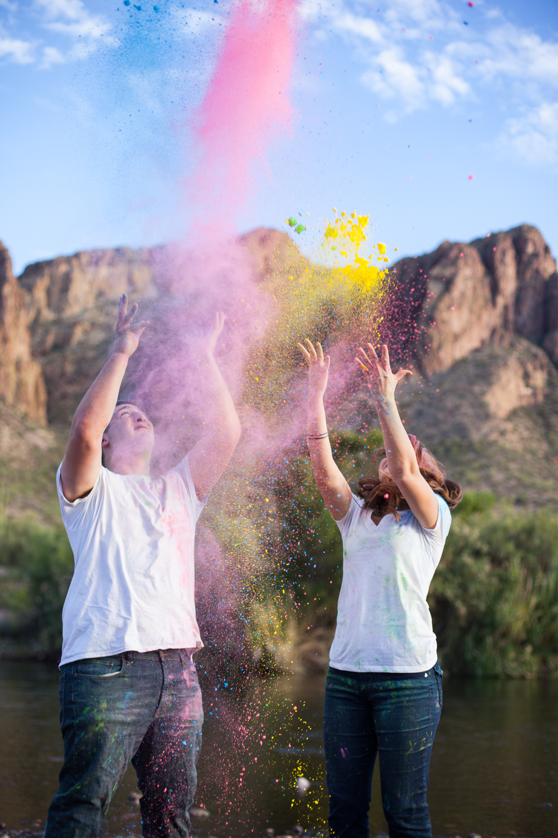 an engaged couple throwing colored powder in the air