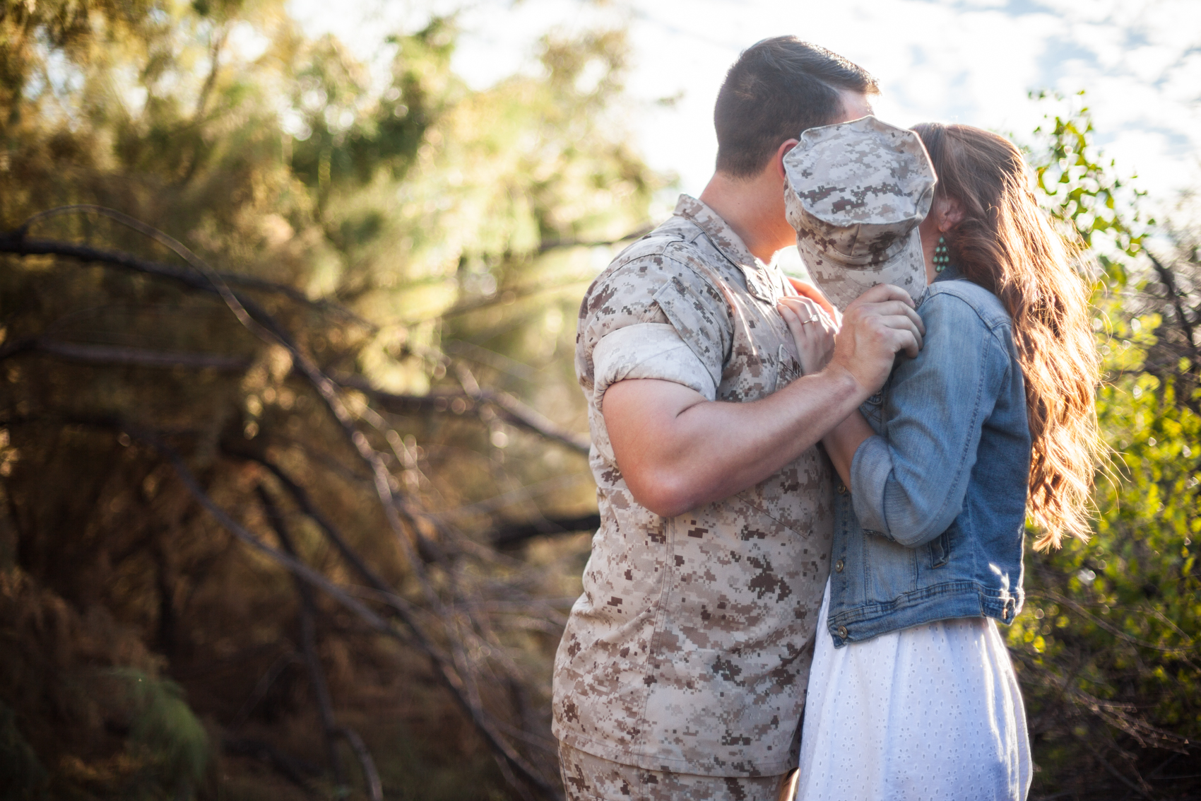 Marine kissing fiance behind his hat in the arizona desert