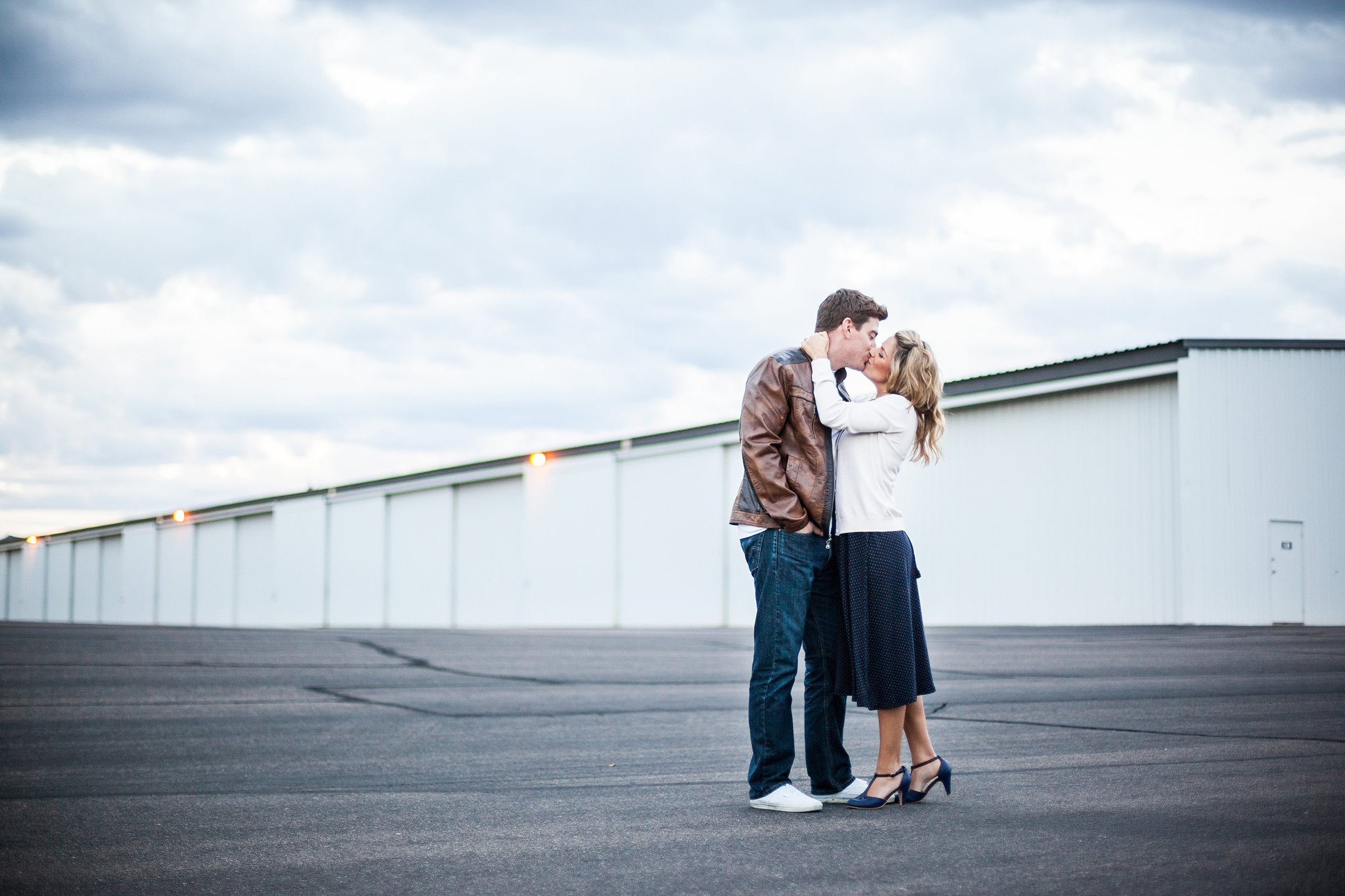 vintage styled couple kissing in airplane hangar alley