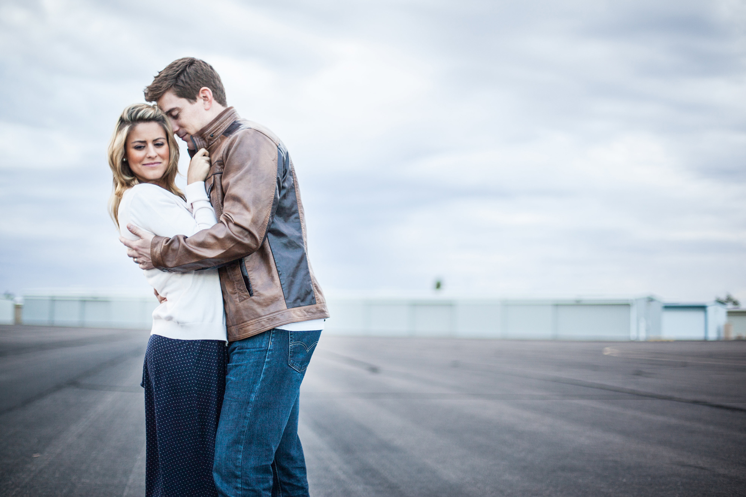 vintage styled couple holding each other in airplane hangar alley