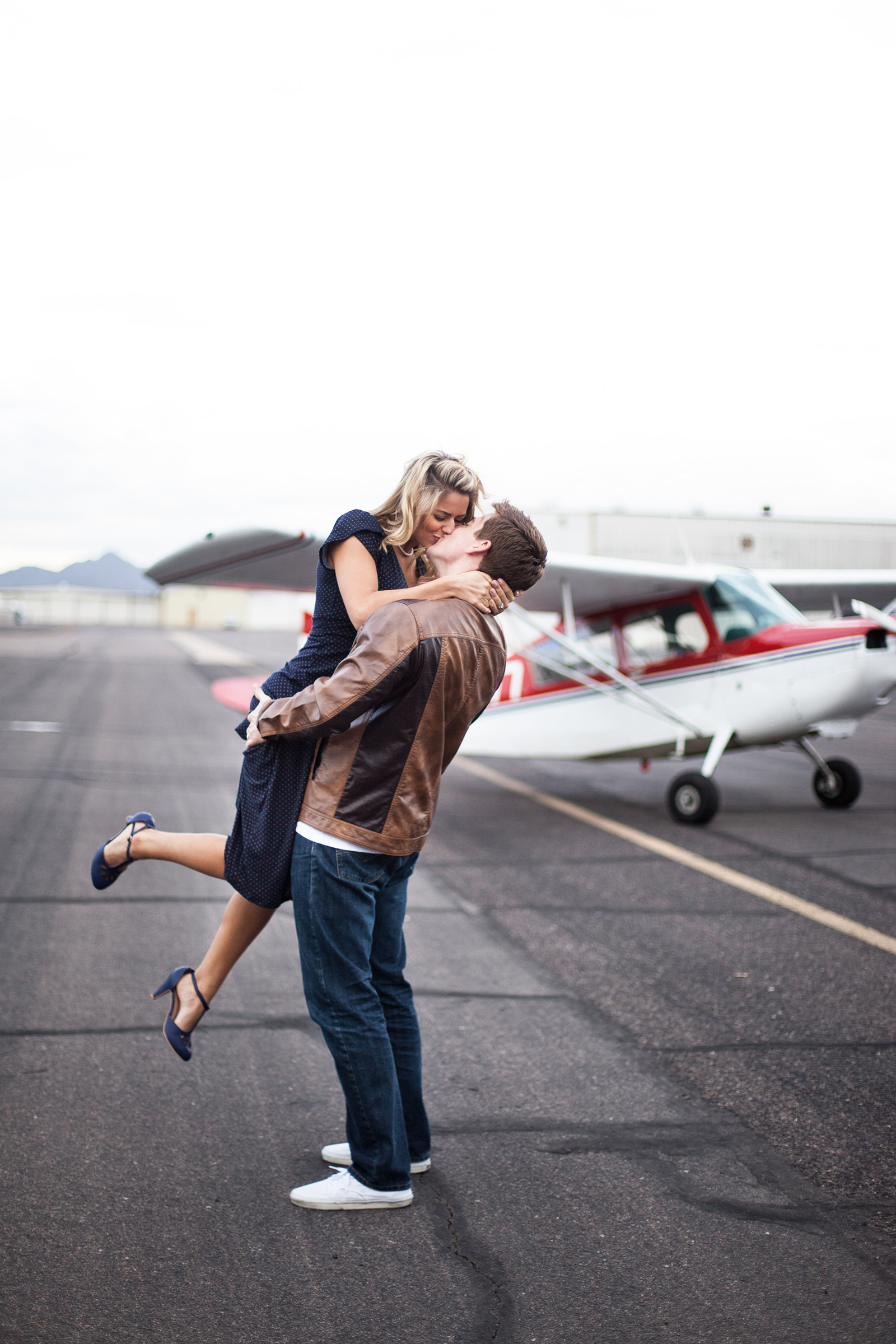 vintage styled couple kissing in front of a vintage airplane
