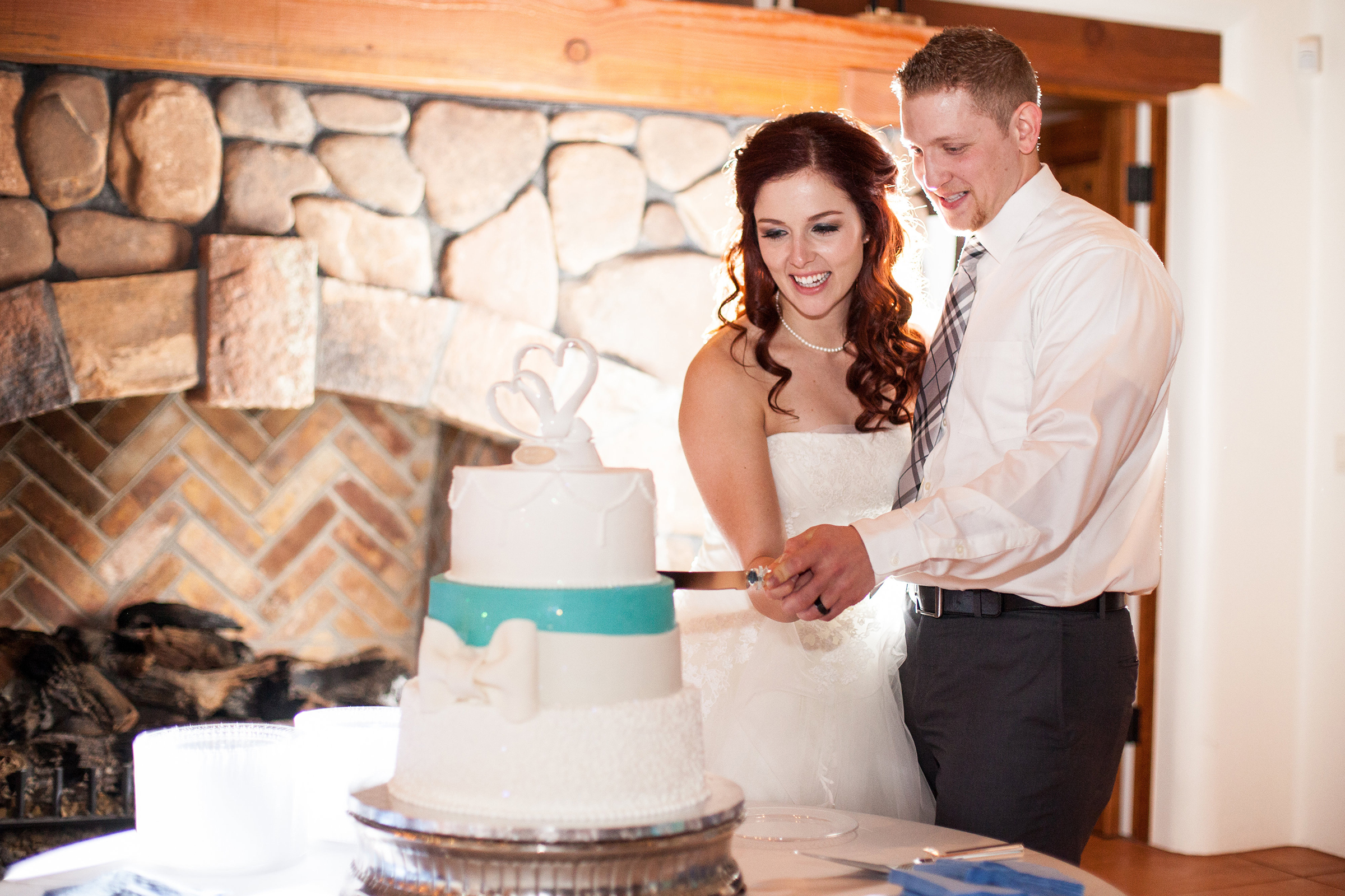 turquoise and white wedding cake cutting with bride and groom