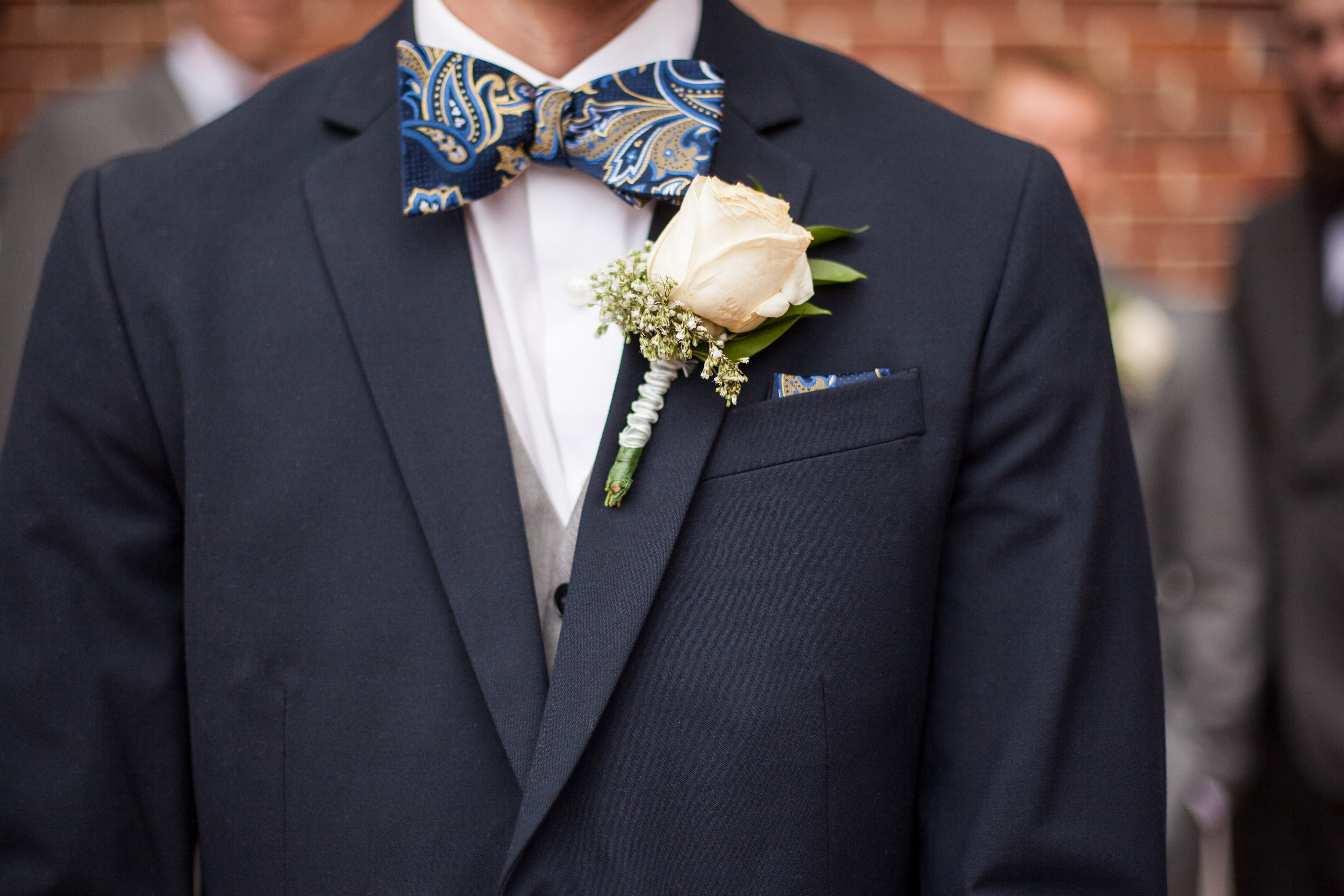 navy blue groom suit with pasiley bowtie and white rose boutonniere