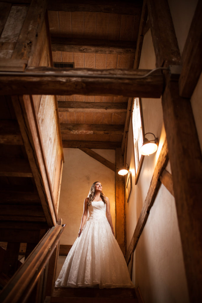 bride in rustic wooden barn looking out the window