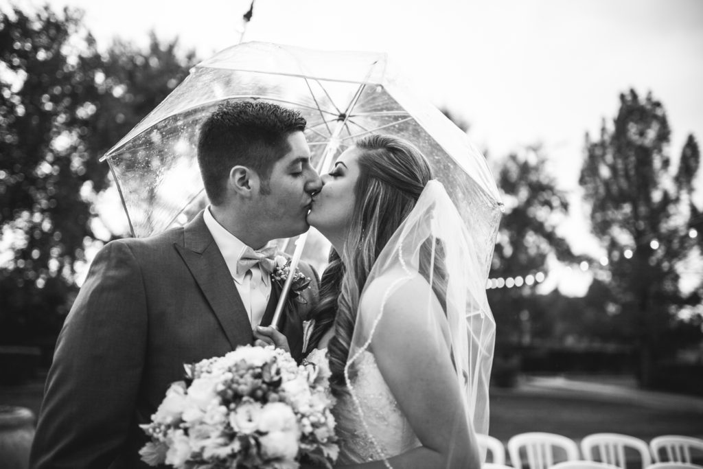 rainy day wedding kiss under a clear umbrella