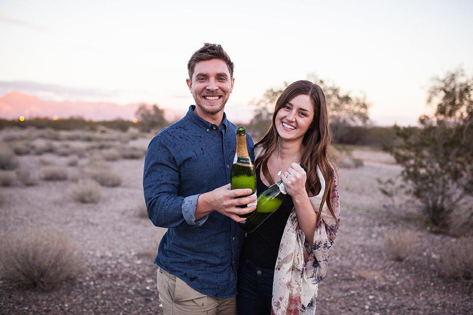 champagne spray fight during engagement session in the desert