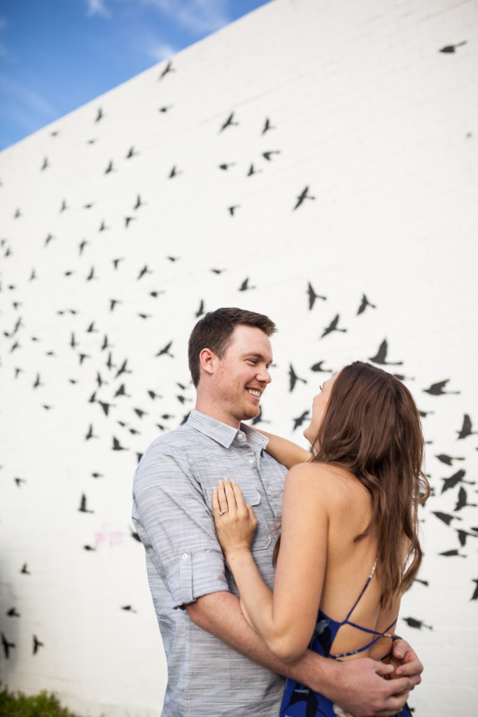 flying birds wall mural engagement photos in downtown phoenix arizona with long flowy blue dress