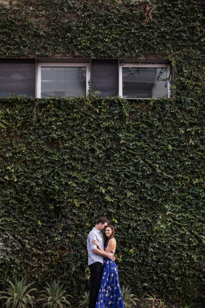 wall of greenery vine covered wall engagement photos engagement pictures in downtown phoenix arizona long flowy blue dress from lulus