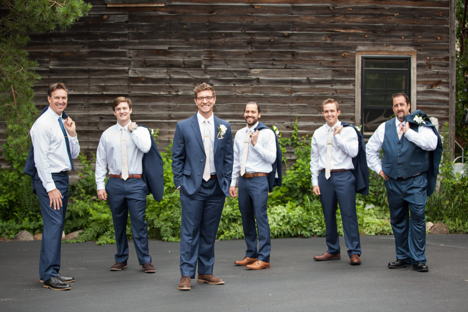 groom and groomsmen in blue suits and pink ties with jackets over shoulders