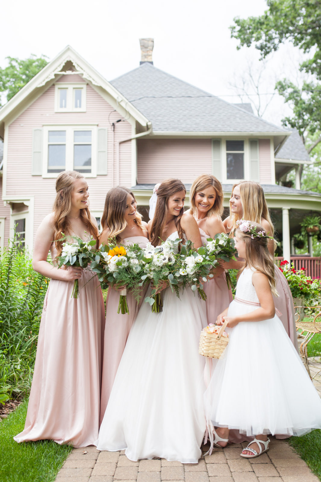 bridesmaids and bride, essence of australia wedding dress from Uptown Bridal outside the pink victorian house at the farm at dover milwaukee with florals by Gia Bella Flowers makeup by Blush by Brittany