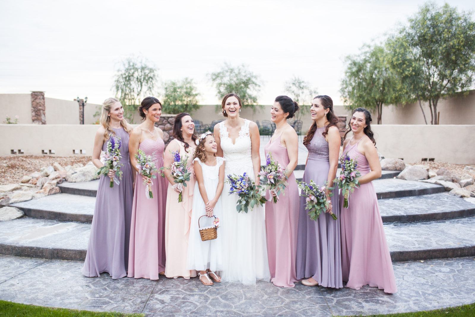 Bride with bridesmaids laughing in pink and purple dresses