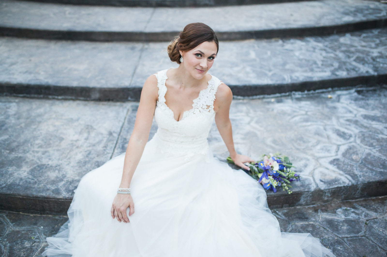 bride with v-neck a-line lace tattoo back wedding dress sitting on steps 
