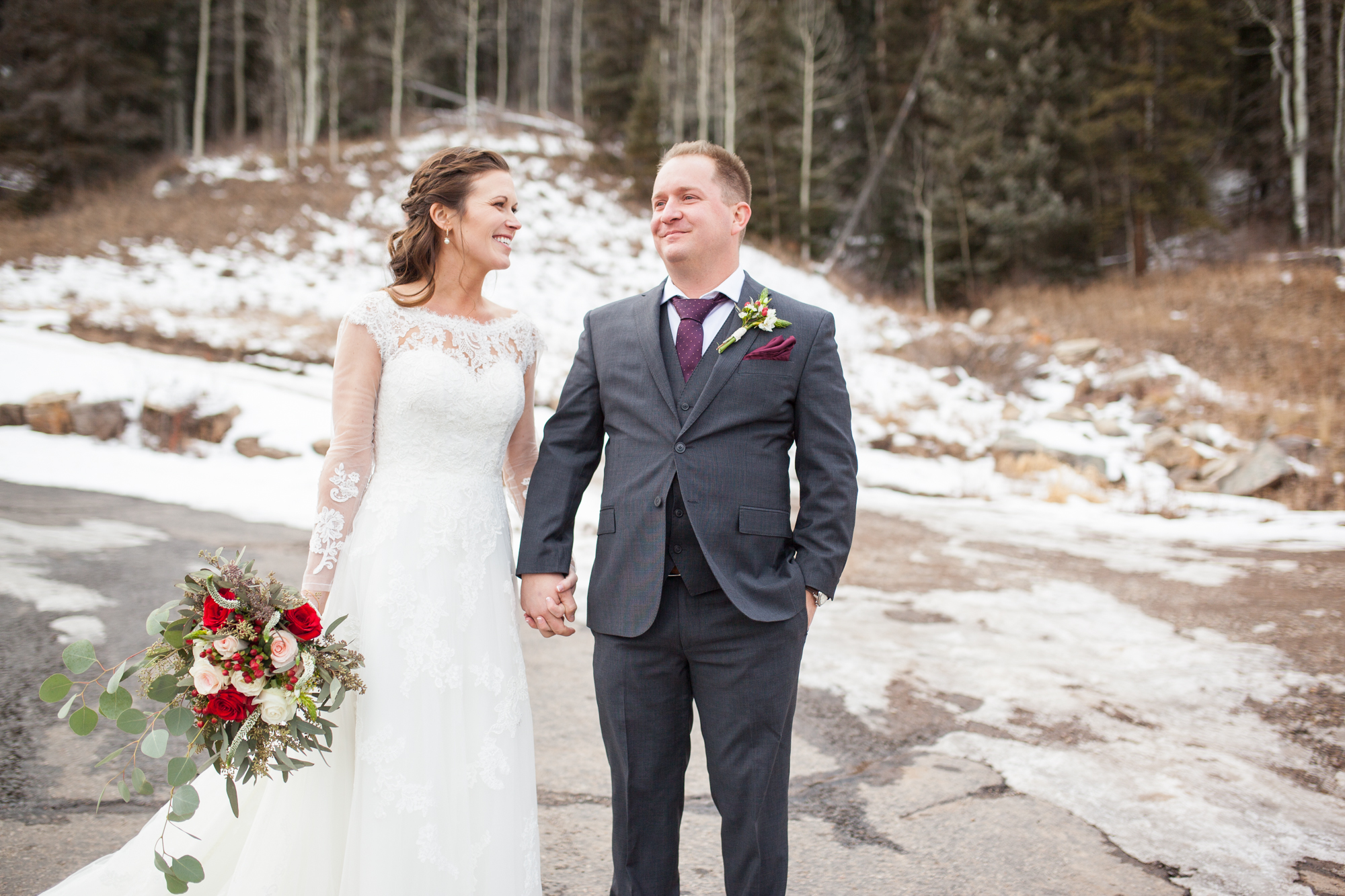 Durango, Colorado Winter Wedding ideas bride and groom in the snow with red rose bouquet and boutonniere
