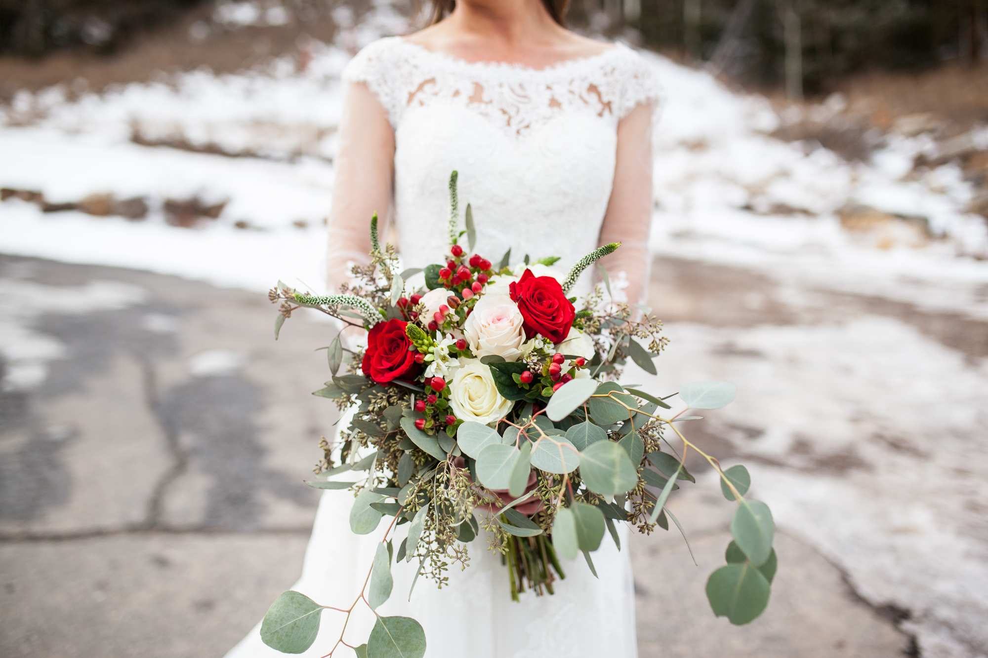 winter bride ideas with long sleeve lace sweetheart wedding dress and red rose bouquet in the snow