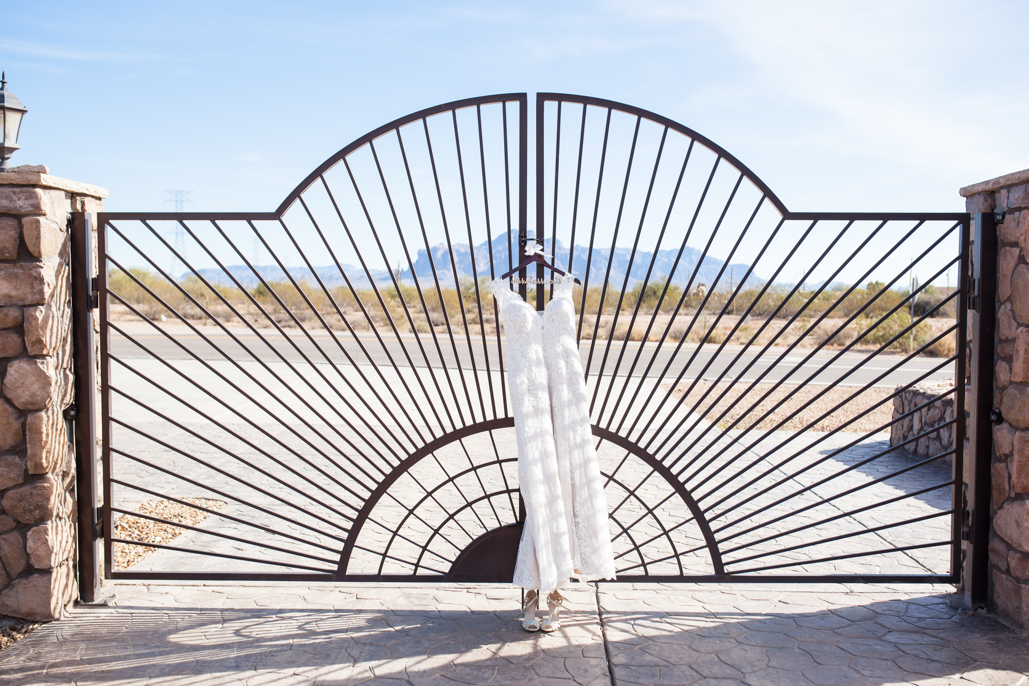 Wedding Dress on gates of Superstition Manor in front of superstition mountains