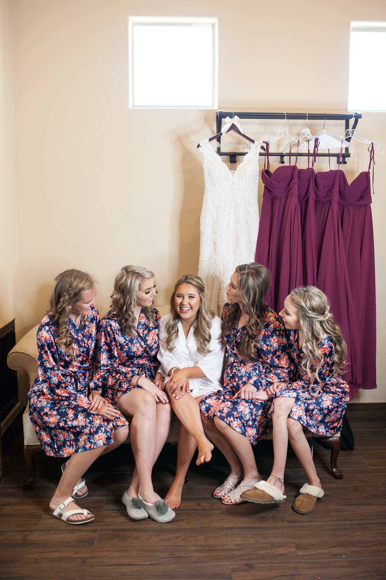 bride and her bridesmaids laughing with dresses in background