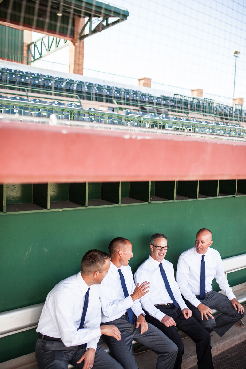 groom and groomsmen in dugout of baseball stadium