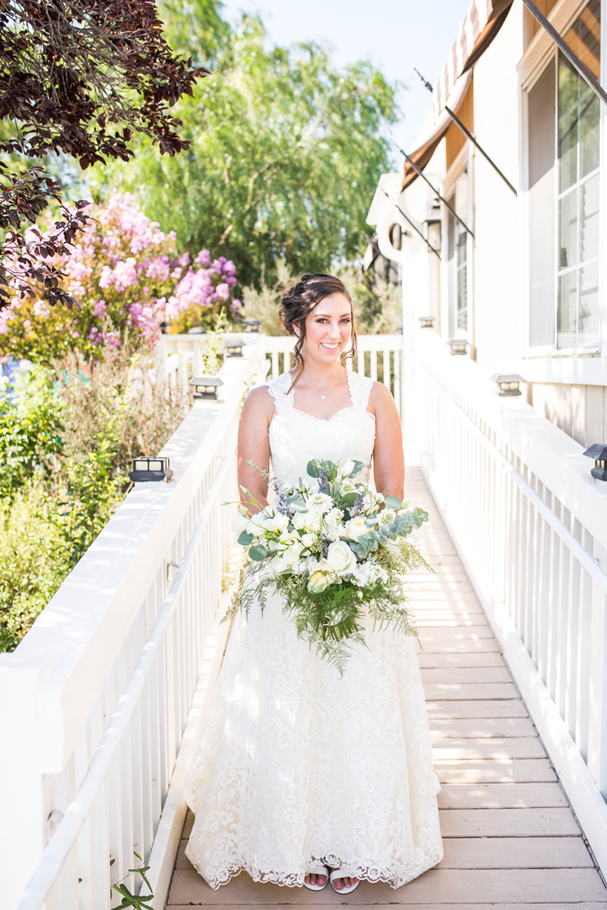 bride in lace wedding dress and large bridal bouquet with greenery and white flowers