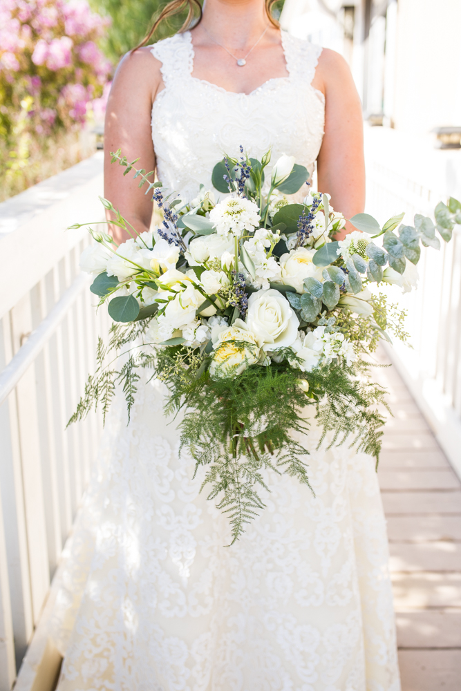 bride in lace wedding dress and large bridal bouquet with greenery and white flowers