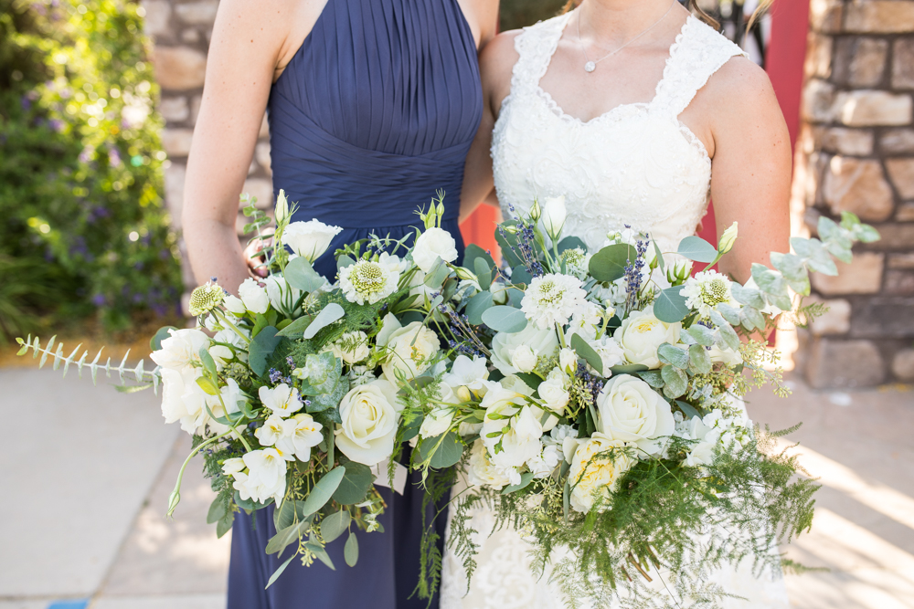bride and bridesmaid with large bridal bouquet with greenery and white flowers