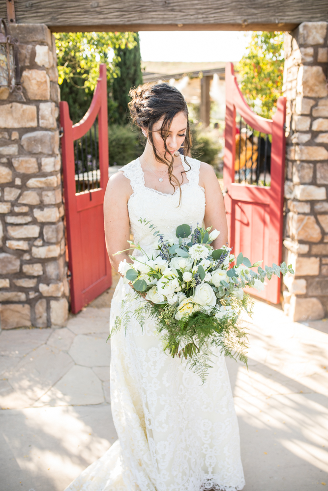 bride in lace wedding dress with large bridal bouquet with greenery and white flowers