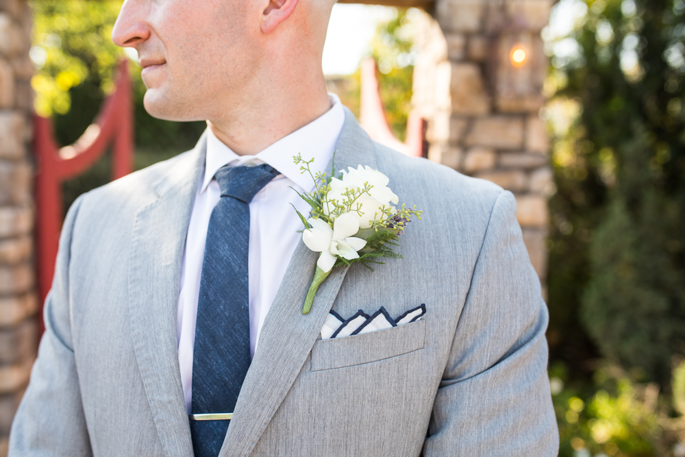 groom in grey suit with navy blue tie and four peak fold pocket square