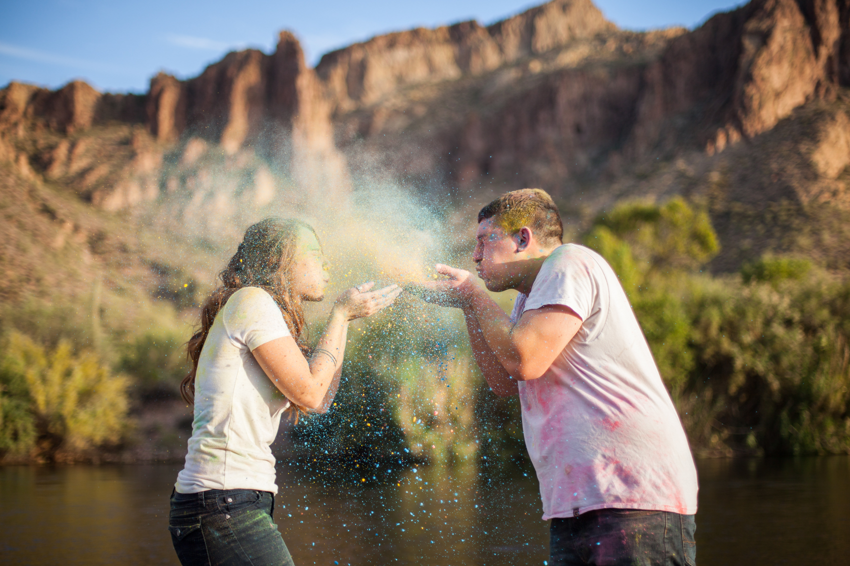 engaged couple blowing colored powder at each other