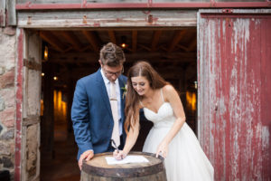 bride and groom signing marriage license in front of barn at the farm at dover milwaukee
