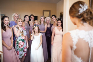 bride's bridesmaids and family looking at her in her wedding dress