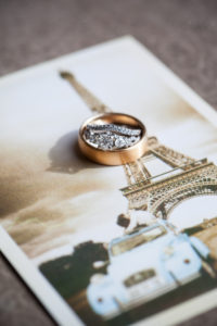 round diamond ring with decorative setting and copper mens wedding band on paris postcard