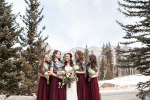 durango colorado winter wedding bridesmaids in maroon skirts with sequin tops and white and red bouquet laughing bridesmaids