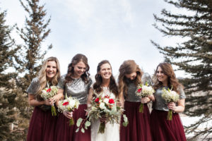 durango colorado winter wedding bridesmaids in maroon skirts with sequin tops and white and red bouquet laughing bridesmaids