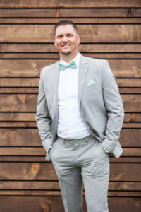 groom in gray suit with teal blue bow tie and pocket square