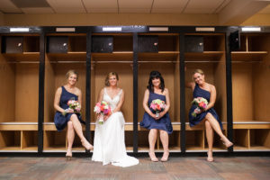 bride and bridesmaids in baseball locker room