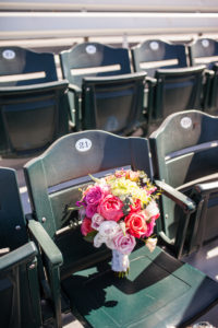 bride bouquet with pink and orange roses in baseball stadium seats