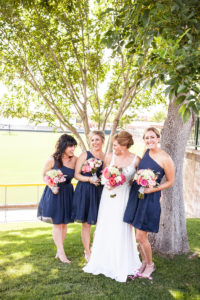 bride with bridesmaids in one shoulder navy blue tea length bridesmaids dresses