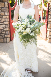 bride in lace wedding dress with large bridal bouquet with greenery and white flowers