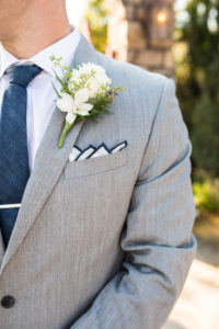 groom in grey suit with navy blue tie and four peak fold pocket square